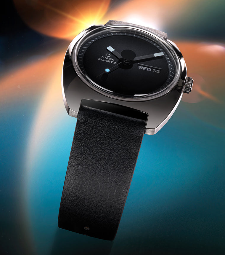 Stylized lifestyle shot of the Q Timex® 1975 Enigma watch floating over a cosmic-themed background. The watch’s sleek design, leather strap, and gleaming case are highlighted with dramatic lighting.