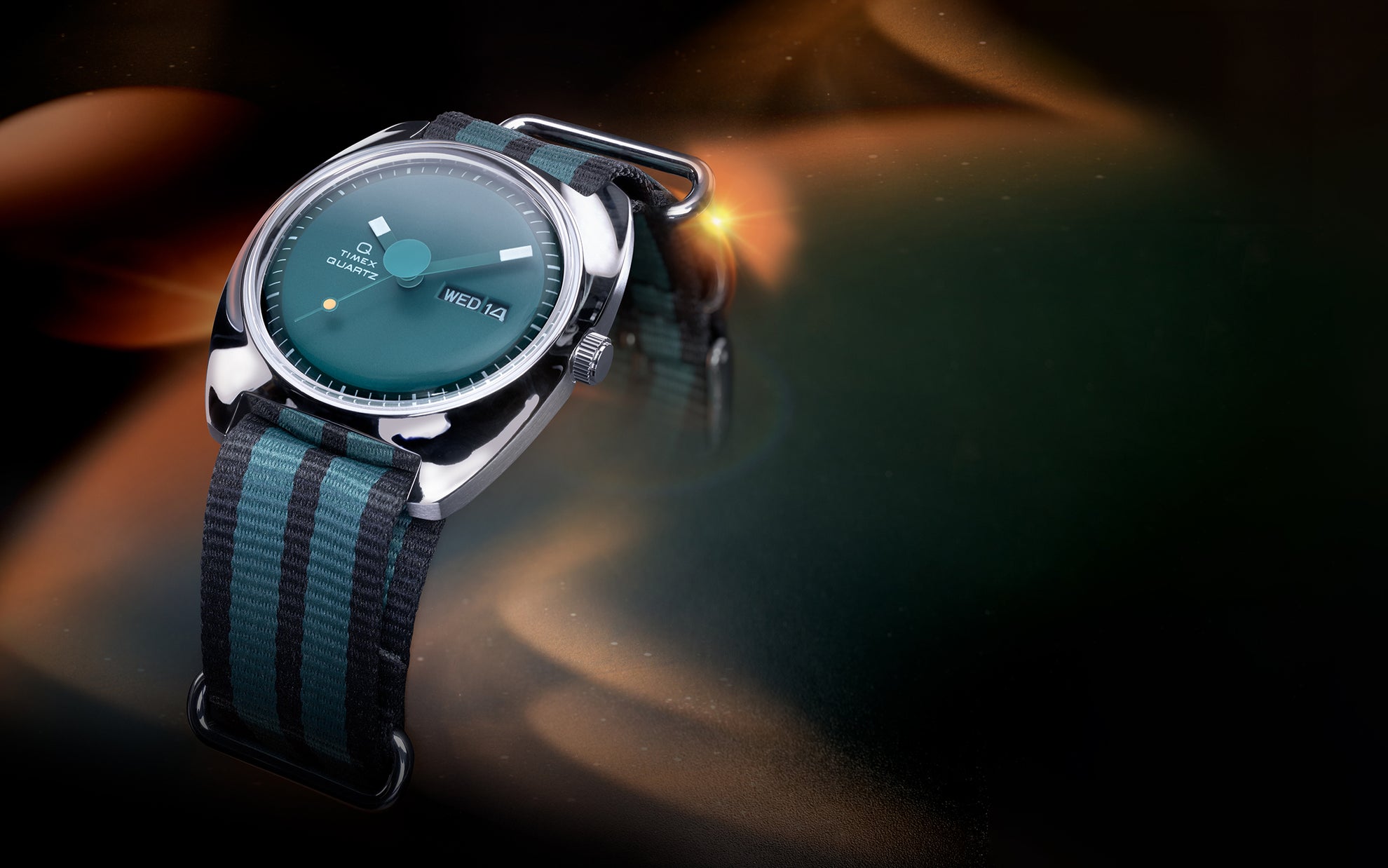 Stylized lifestyle image of the Q Timex® 1975 Enigma watch with a green dial and striped black-and-green fabric strap, illuminated by ambient orange and teal lighting against a cosmic-style background.