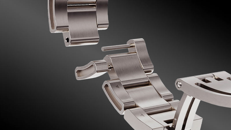 A detailed close-up image of a stainless steel watch bracelet from the Timex Waterbury Chronograph, showing the adjustable clasp mechanism and removable links with a visible spring bar pin, highlighting its precision engineering and high-quality finish against a dark gradient background.