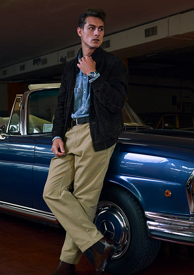 Model leaning on a vintage blue convertible wearing a Q Timex® Chronograph with blue dial and leather strap.
