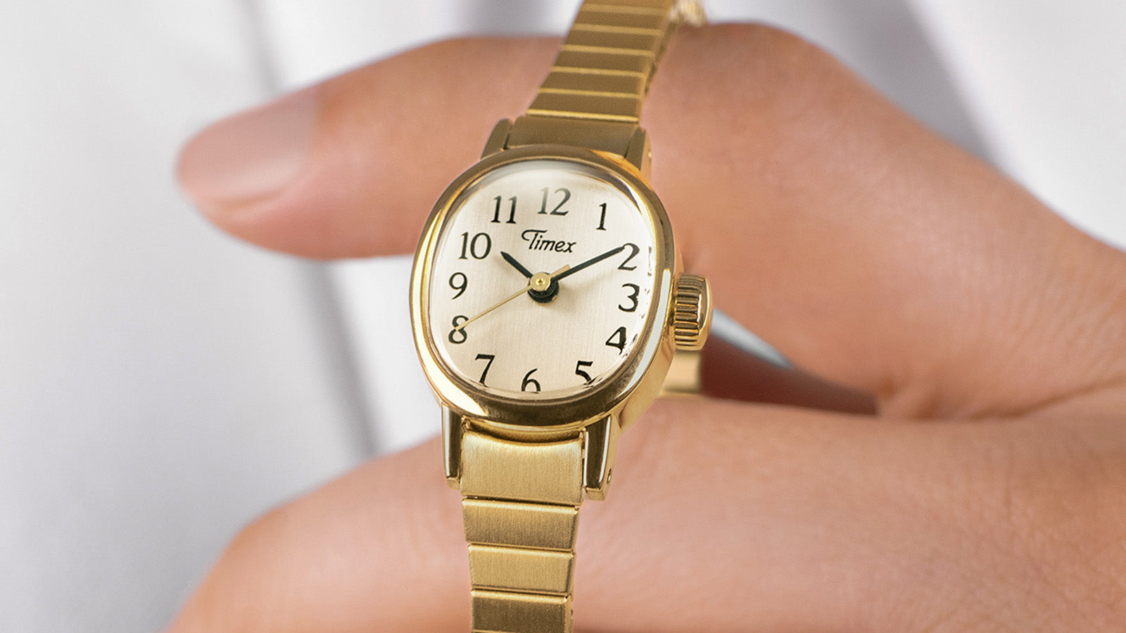 Detailed front view of the Timex Cavatina Mini gold-tone watch, showing the oval white dial with black numerals and gold hands.