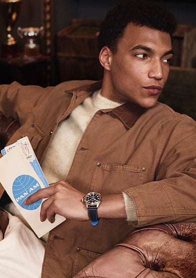 Model wearing the Timex x Pan Am® Waterbury Ace while holding vintage Pan Am travel documents, evoking mid-century air travel style.