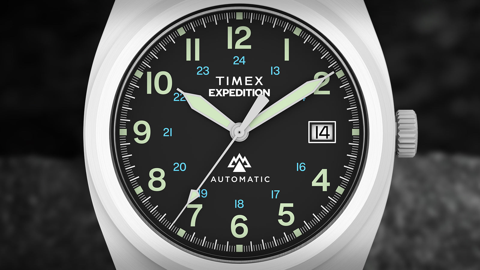 Close-up of the Timex Expedition® Capstone Automatic dial showing luminous green numerals, blue 24-hour markings, and bold hands with glow accents. The design captures functional clarity and adventure-ready craftsmanship.