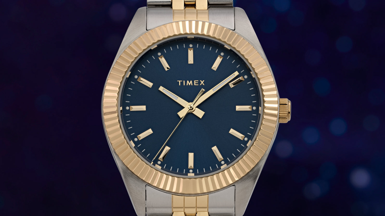 Close-up of the Timex Legacy watch face featuring a deep blue sunray dial, gold-tone indices, and matching hands with a sleek fluted bezel.