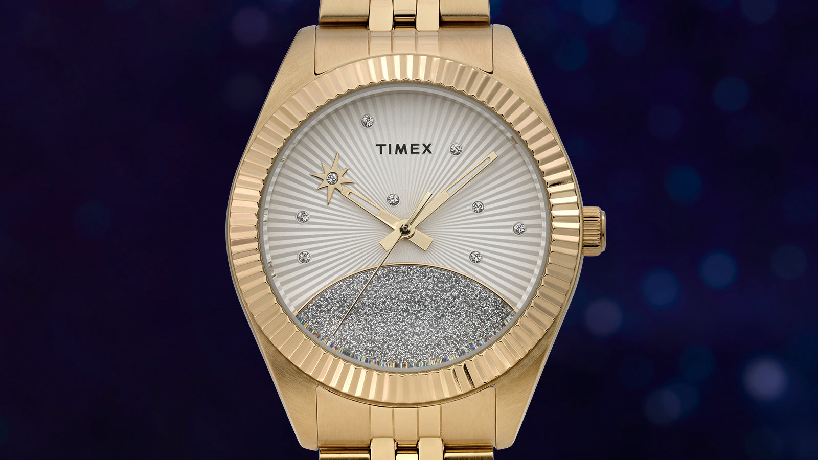 Close-up of the Timex Legacy watch dial with gold-tone hands, starburst detailing, crystal hour markers, and a sparkling silver half-moon design.