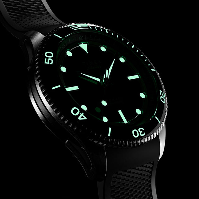 Detailed close-up of Timex Atelier automatic watch highlighting the knurled bezel edge, polished steel case, and crown engraved with the Timex “T” logo.