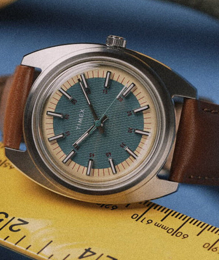 Watch on its side with a ruler underneath the watch