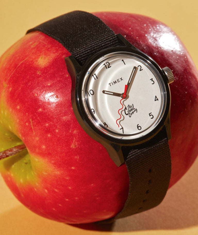 A watch wrapped around a shiny red apple