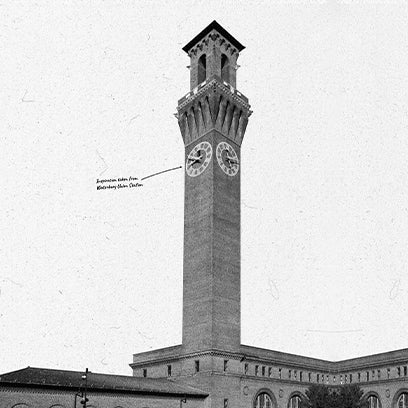 Black-and-white photograph of a tall brick clock tower with twin clock faces. A hand-drawn arrow identifies the clock’s origin as “Expensive dials from Waterbury Watch Co.” — a nod to the historical significance of Timex craftsmanship.