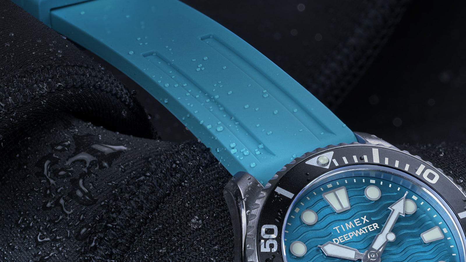 Detailed close-up of the aqua blue silicone strap of the Timex Deepwater Meridian 200 with water droplets.