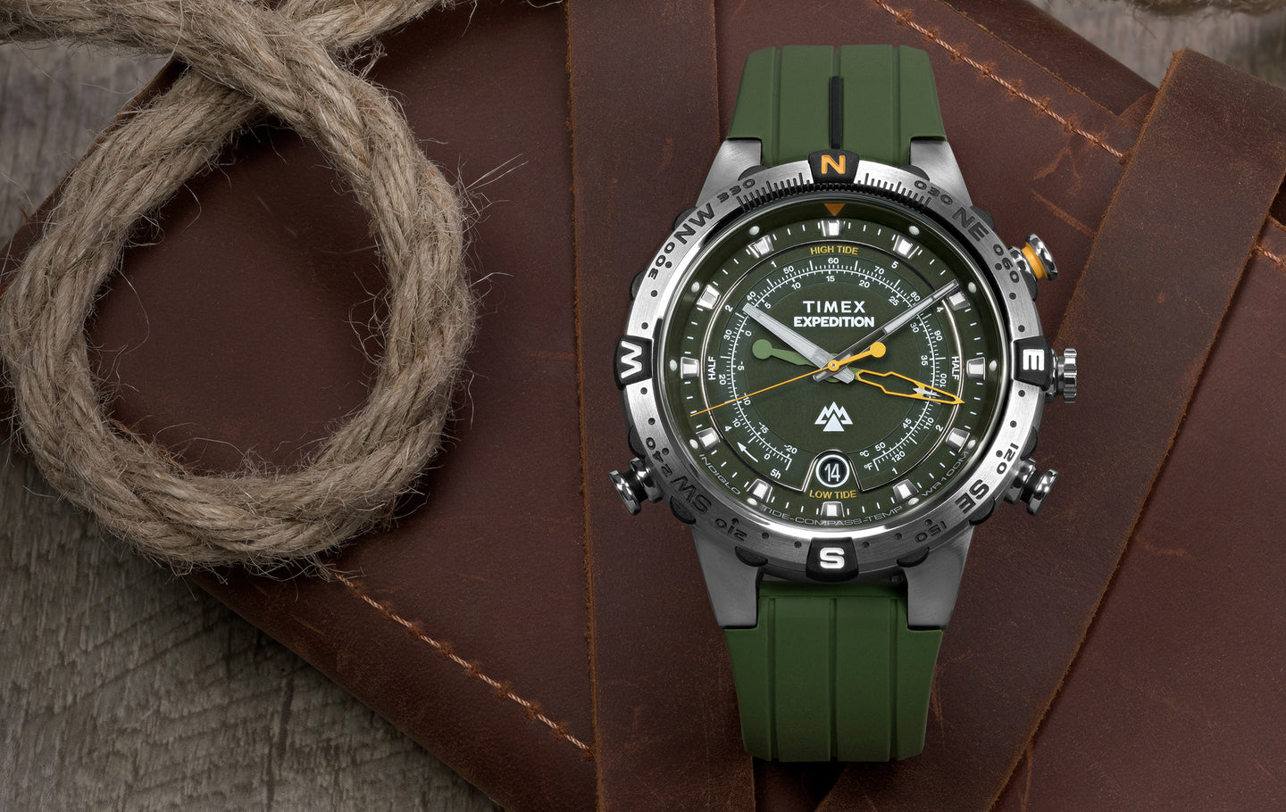 Timex Expedition® Field Post Solar watch with black dial, white numerals, date window at 3 o’clock, and black fabric strap, resting on a brown leather surface.