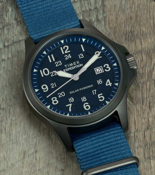 Close-up of the watch face showing bold white Arabic numerals, luminous hands, 24-hour inner track, date window at 3 o’clock, and “Solar Powered” marking.