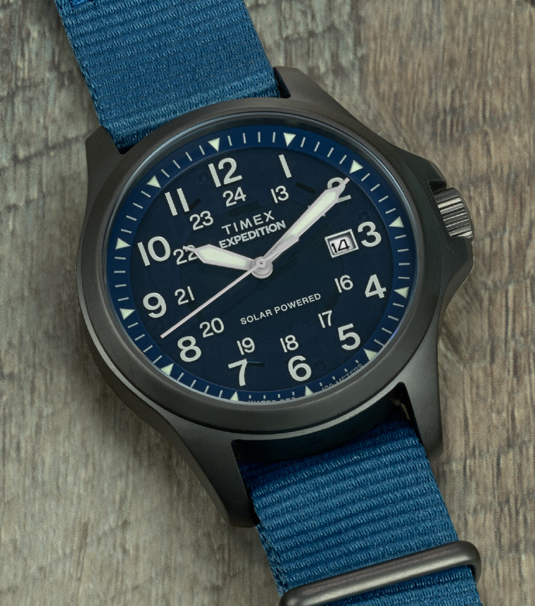 Close-up of the watch face showing bold white Arabic numerals, luminous hands, 24-hour inner track, date window at 3 o’clock, and “Solar Powered” marking.