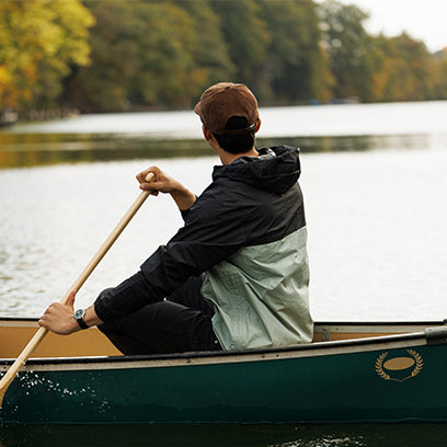 A man paddles a canoe on a calm lake, wearing the Expedition® Field Post Solar watch, blending function with outdoor adventure.