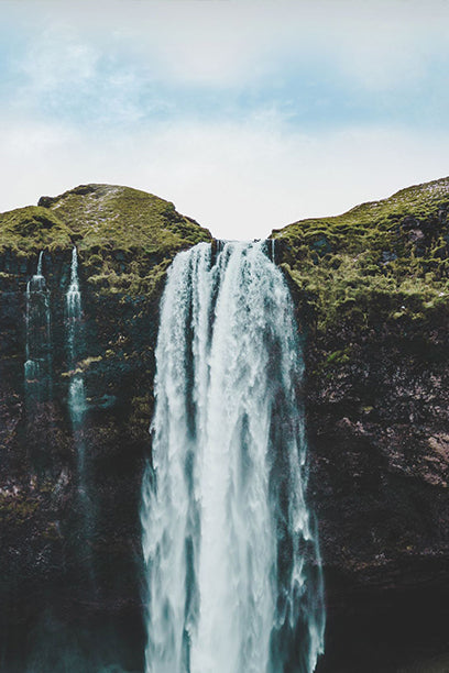 A tall, powerful waterfall cascading between green cliffs, symbolizing rugged natural energy.