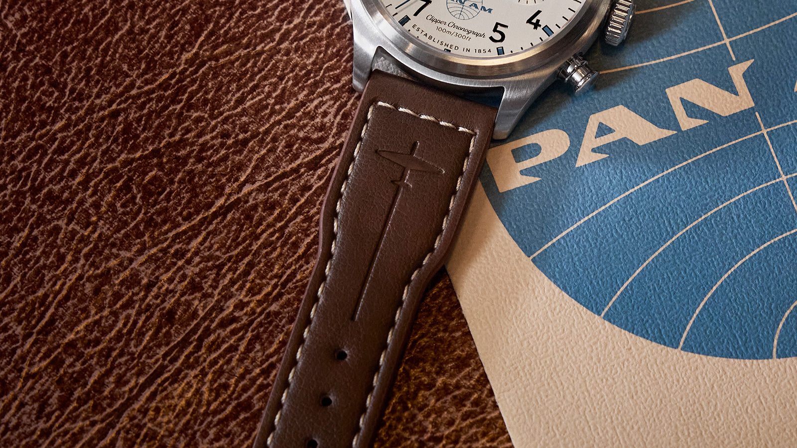 Close-up of the brown leather strap of the Timex x Pan Am® Waterbury Ace Chronograph with embossed airplane motif and white stitching.