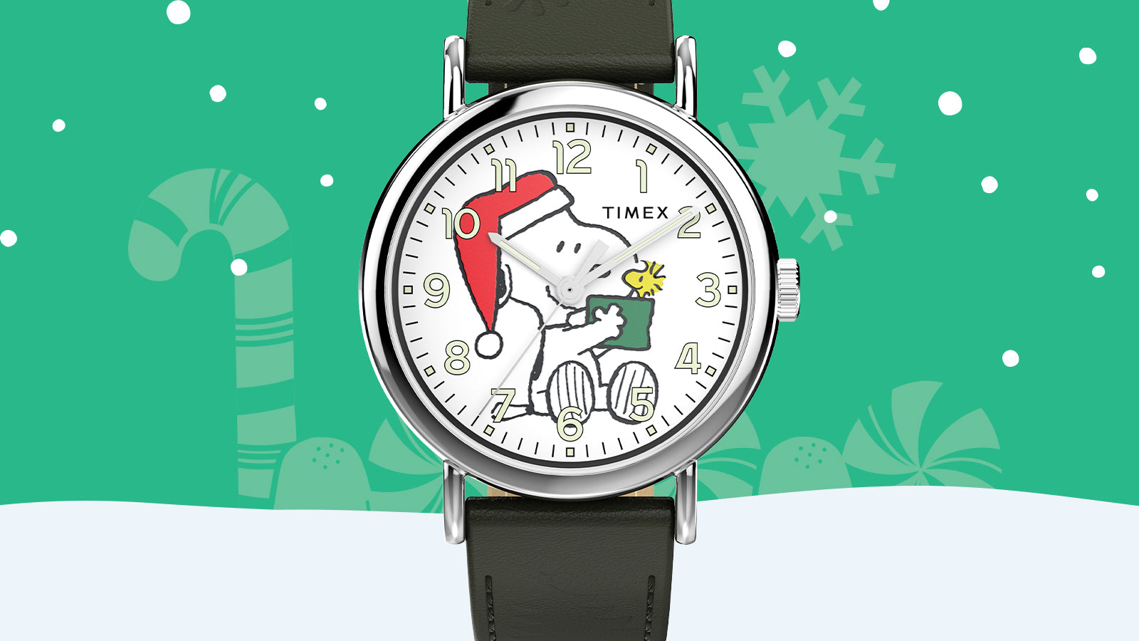 Timex x Peanuts® Weekender Holiday Dial watch featuring Snoopy in a Santa hat holding a gift for Woodstock, on a white dial with gold-tone numerals and a dark green leather strap. Background shows green with snowflakes and candy canes.