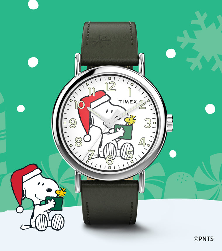Timex x Peanuts® Weekender Holiday Dial watch beside an illustration of Snoopy in a Santa hat holding a gift for Woodstock, set against a festive green background with snowflakes and candy canes.