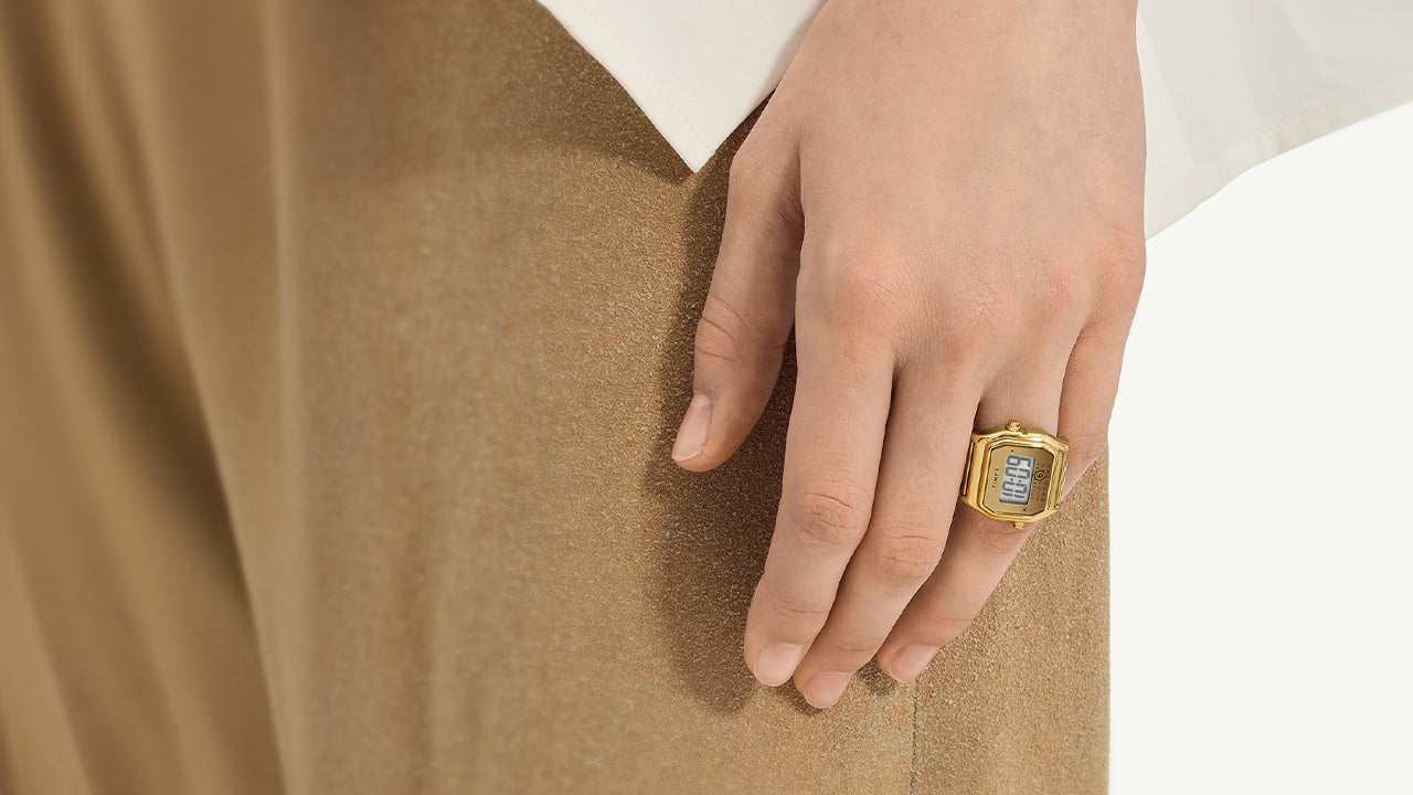 Editorial image of the Timex x MM6 Maison Margiela T80 collaboration, showcasing the gold digital ring watch styled on hand and individually displayed. The design celebrates a bold reinterpretation of Timex’s vintage T80 aesthetic through MM6’s conceptual lens.