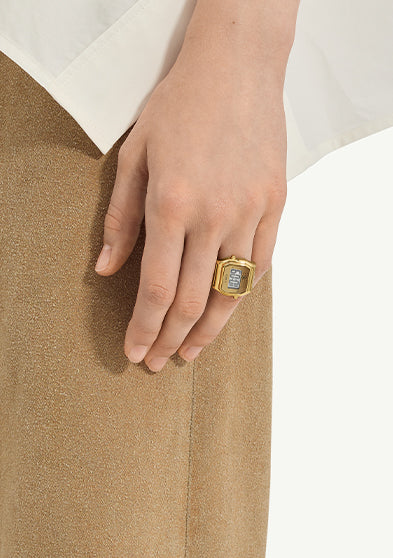 Editorial image of the Timex x MM6 Maison Margiela T80 collaboration, showcasing the gold digital ring watch styled on hand and individually displayed. The design celebrates a bold reinterpretation of Timex’s vintage T80 aesthetic through MM6’s conceptual lens.