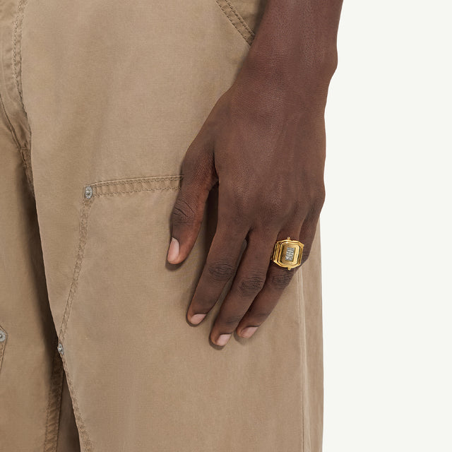Close-up shot of a hand wearing the Timex x MM6 Maison Margiela T80 digital watch ring in gold. The accessory combines Timex’s signature digital display design with MM6’s avant-garde jewelry concept, shown styled with neutral-toned clothing.