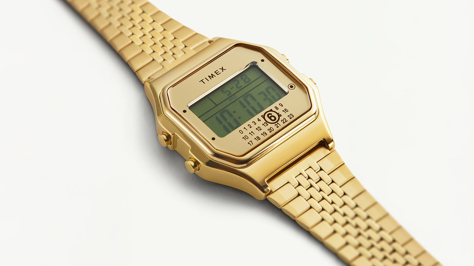 Detailed close-up of the Timex x MM6 T80 digital display and gold-tone bezel, emphasizing its minimal layout, numeric date wheel, and polished metallic finish.