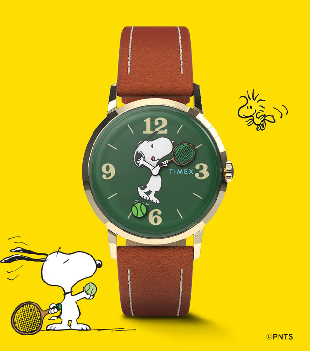 A Timex Marlin® Hand-Wound x Snoopy Tennis watch with a green dial and brown leather strap set against a bright yellow background. The dial features Snoopy holding a tennis racket, with a tennis ball design near 6 o’clock, celebrating the Peanuts tennis theme.