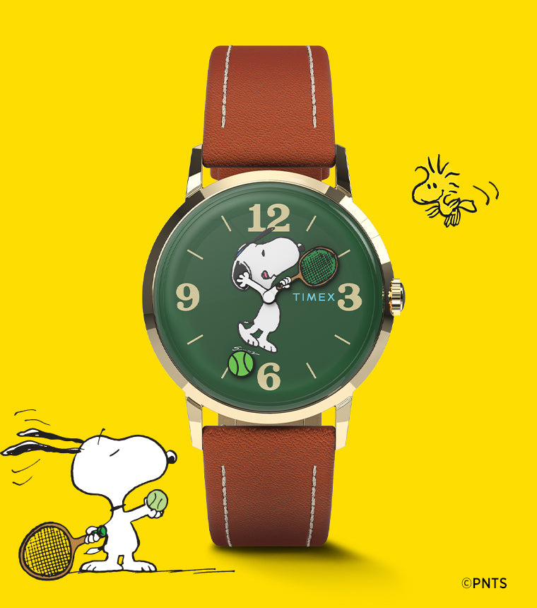 A Timex Marlin® Hand-Wound x Snoopy Tennis watch with a green dial and brown leather strap set against a bright yellow background. The dial features Snoopy holding a tennis racket, with a tennis ball design near 6 o’clock, celebrating the Peanuts tennis theme.