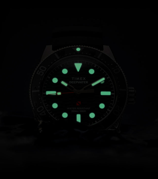 Timex Deepwater Reef 200 watch glowing in darkness, with bright green lume on the hands and hour markers, emphasizing superior underwater visibility.