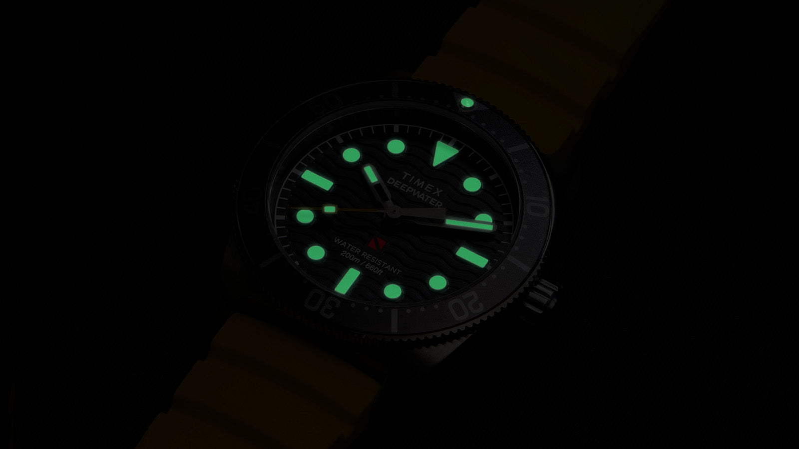 Timex Deepwater Reef 200 dive watch glowing in the dark, showing luminous hands and hour markers for enhanced underwater visibility.