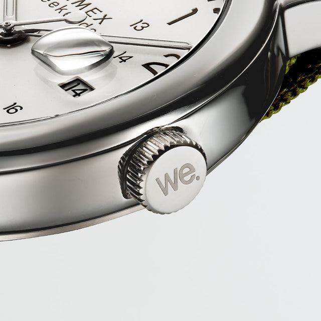 Close-up of the Timex Weekender’s crown engraved with “we.” next to the white dial and date window.