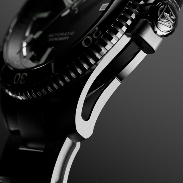 Macro side view of Timex Atelier watch case with brushed stainless steel finish, detailed crown engraved with "T" logo, and knurled bezel edge.