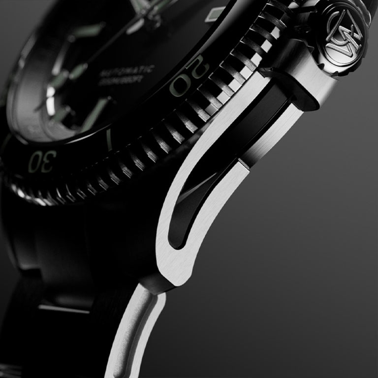 Macro side view of Timex Atelier watch case with brushed stainless steel finish, detailed crown engraved with "T" logo, and knurled bezel edge.
