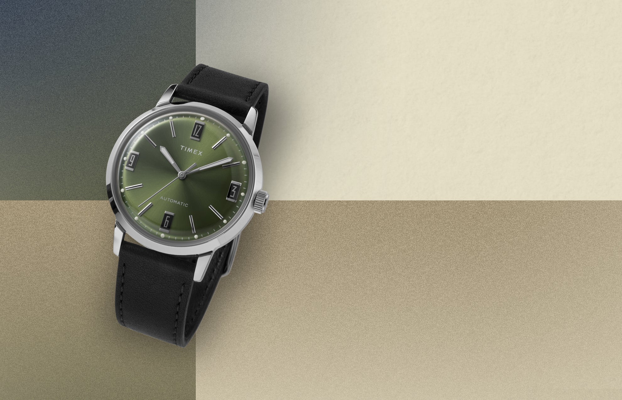 Timex Marlin Automatic watch with green sunray dial and black leather strap displayed on a beige and olive color block background.
