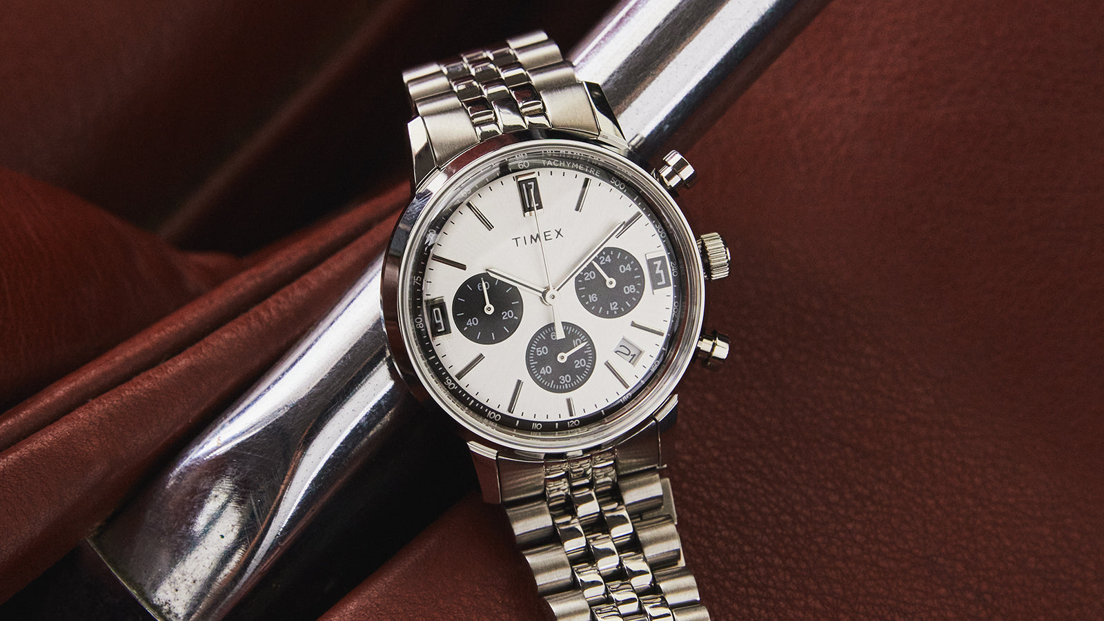 Timex Marlin Chronograph Tachymeter resting on brown leather seat, featuring three black subdials and tachymeter scale.