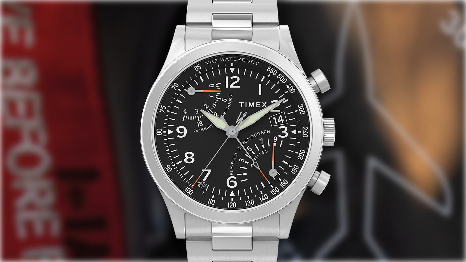 Front view of the Timex Waterbury Traditional Fly-Back Chronograph showcasing the black dial with white numerals, orange accents, and date display.