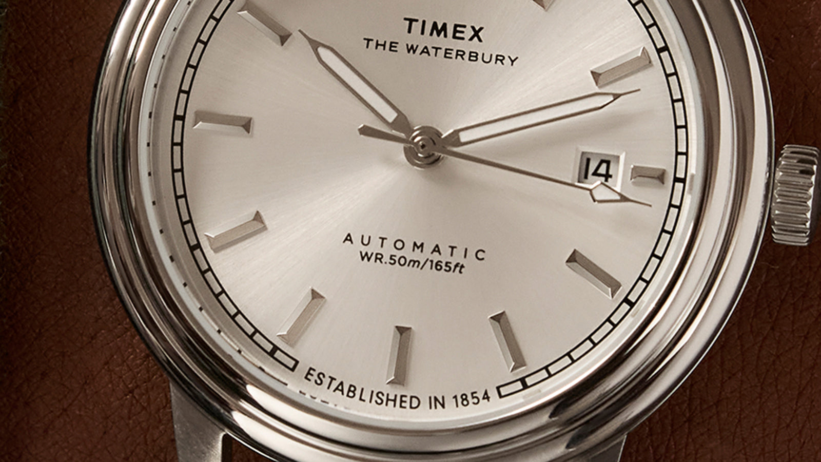 Close-up of the Timex Waterbury Metropolitan Automatic dial showing applied hour markers, slim hands, and date window at 3 o’clock.