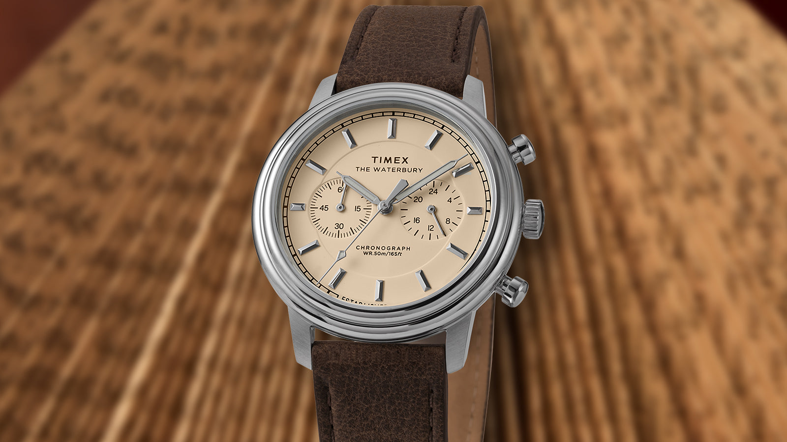 Front view of the Timex Waterbury Metropolitan Chronograph featuring cream dial, polished stainless steel case, and brown leather strap.