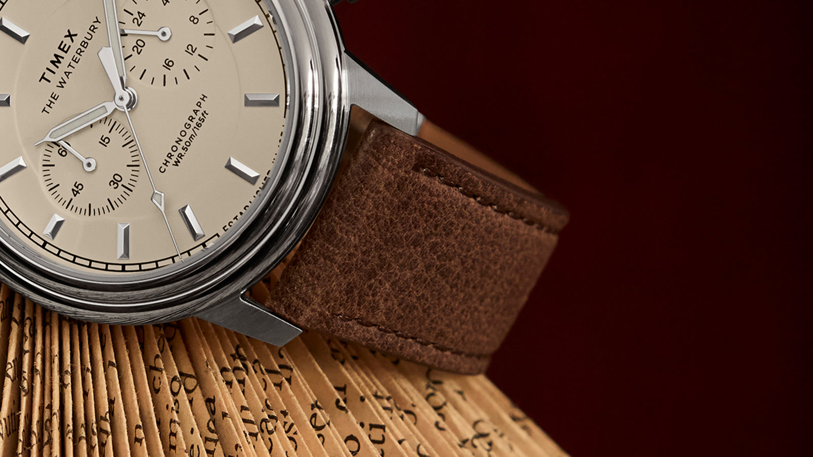 Close-up of the Timex Waterbury Metropolitan Chronograph showing detailed brown leather strap stitching and polished case finish.