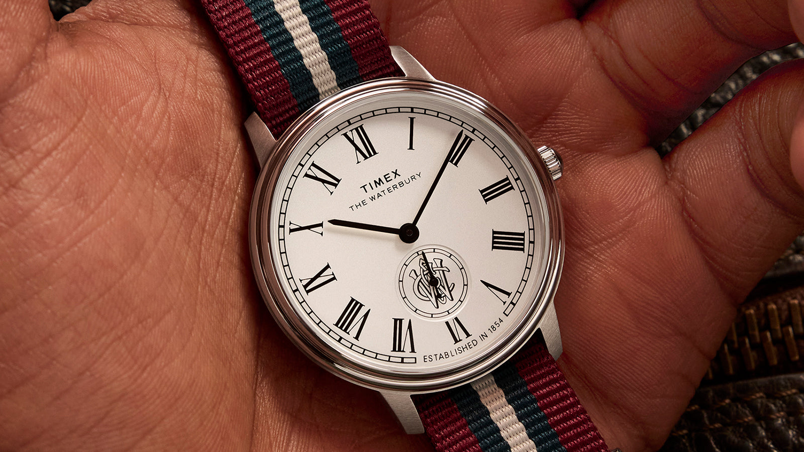 Timex Waterbury Metropolitan Sub-Second with white dial, Roman numerals, and multicolor fabric strap resting in hand.