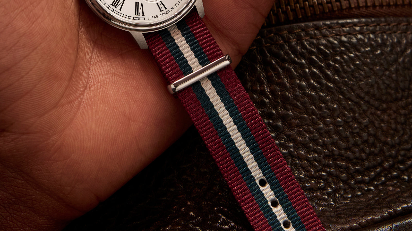 Detailed view of the Timex Waterbury Metropolitan Sub-Second’s red, white, and blue-striped fabric strap against a textured leather background.