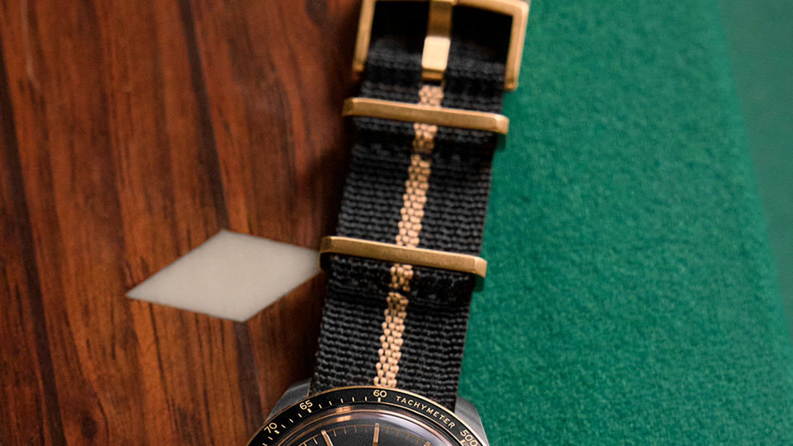Detailed view of the Timex Waterbury Heritage Chronograph black fabric strap with a tan center stripe and gold-tone buckle.
