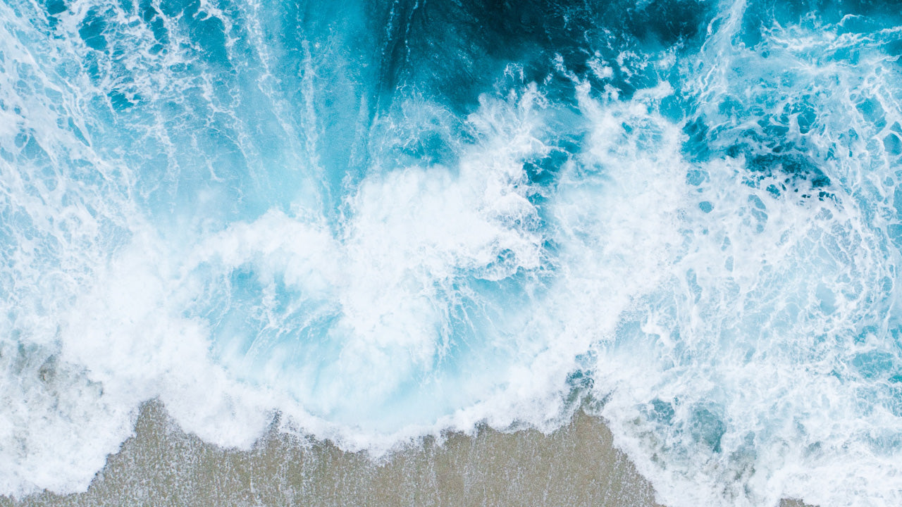 Aerial view of ocean waves crashing against the shore, symbolizing the marine inspiration behind the TIMEX® Legacy Ocean #tide watch.