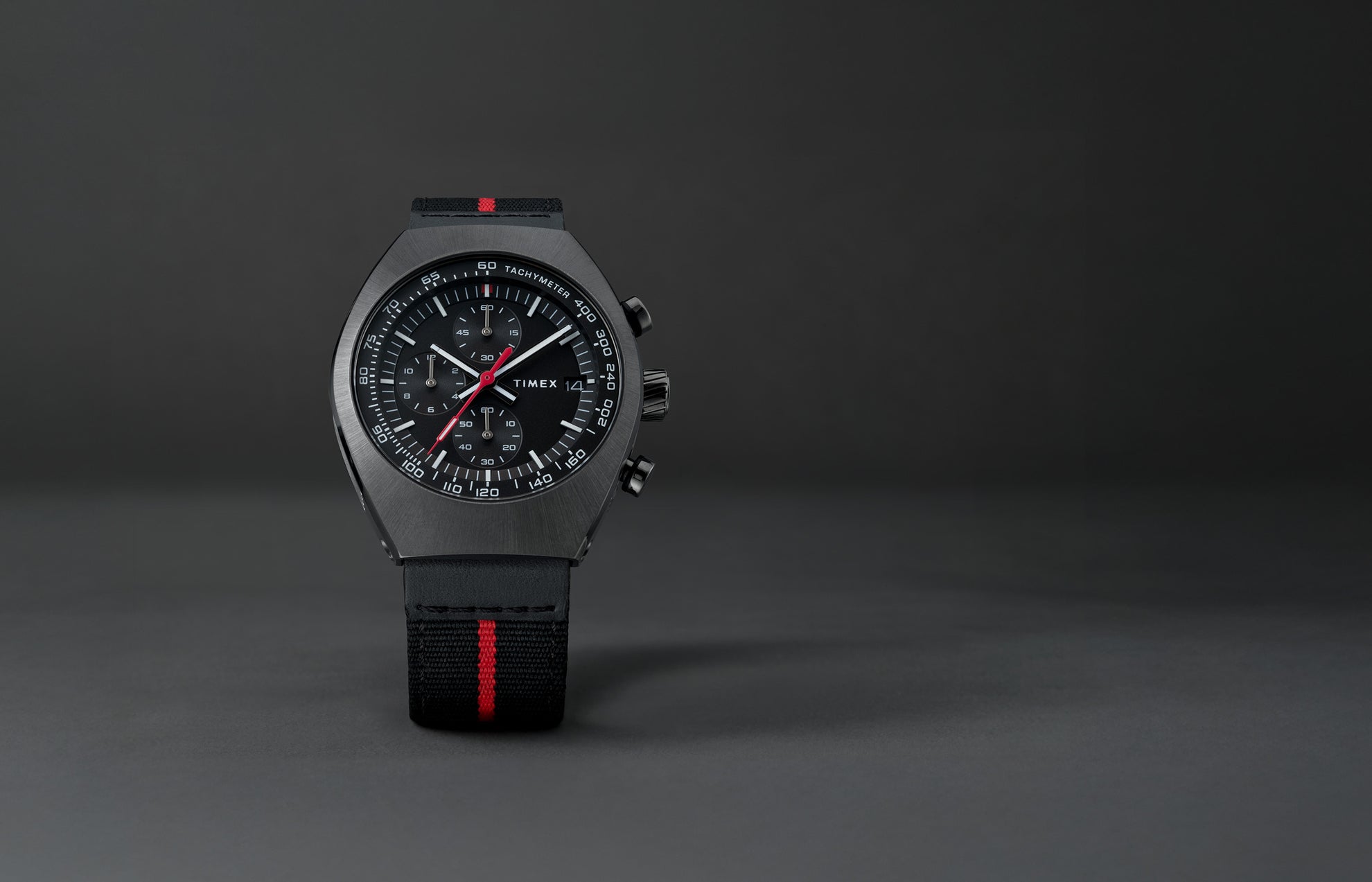 Front view of the Timex Legacy Tonneau Chronograph showing black dial with white markers, red seconds hand, and tachymeter scale.