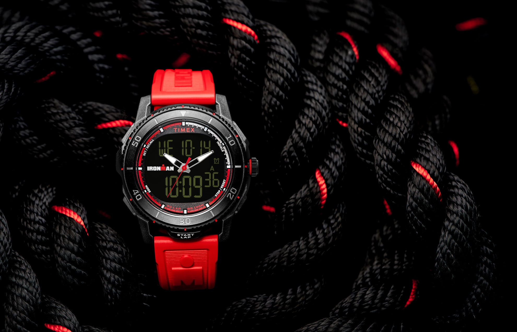 TIMEX® IRONMAN® Adrenaline Ana-Digi watch with black case, red accents, and red resin strap displayed on coiled black rope with red details.