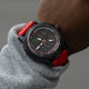 TIMEX® IRONMAN® Adrenaline Ana-Digi watch with red strap worn on wrist, showing analog-digital display and black bezel with red markings.