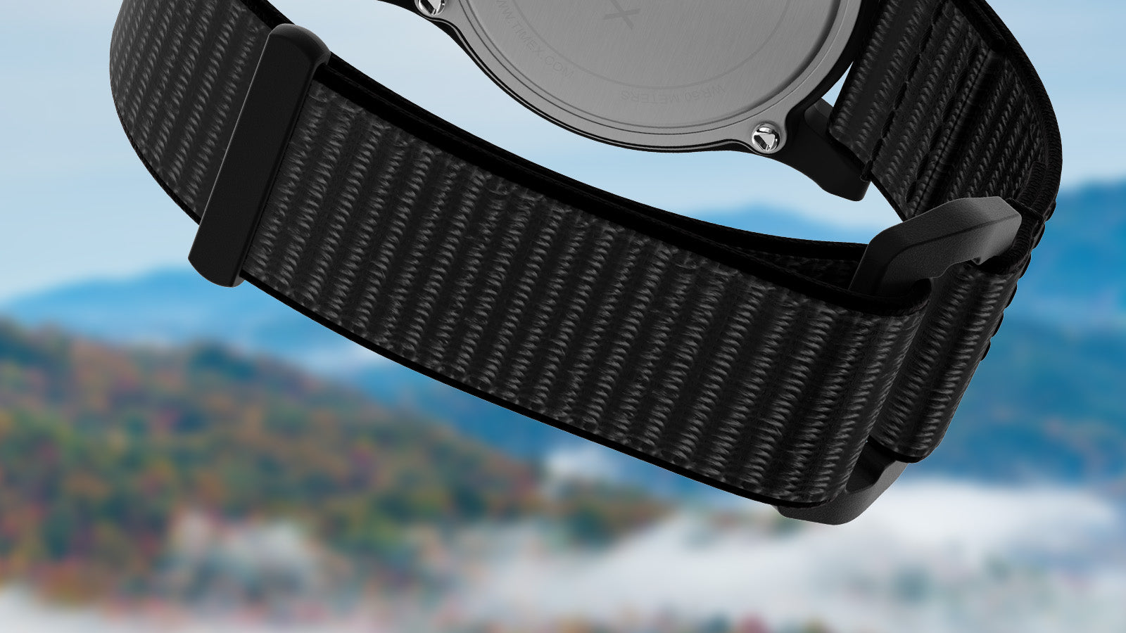 Close-up of the black woven fabric strap and buckle of the Timex Great Smoky Mountains National Park watch, with the misty blue mountains blurred in the background.