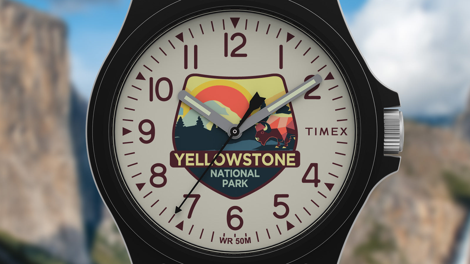 Close-up of the Timex Yellowstone National Park watch face with mountain and sunset artwork, including a stylized bison and bold maroon numerals.