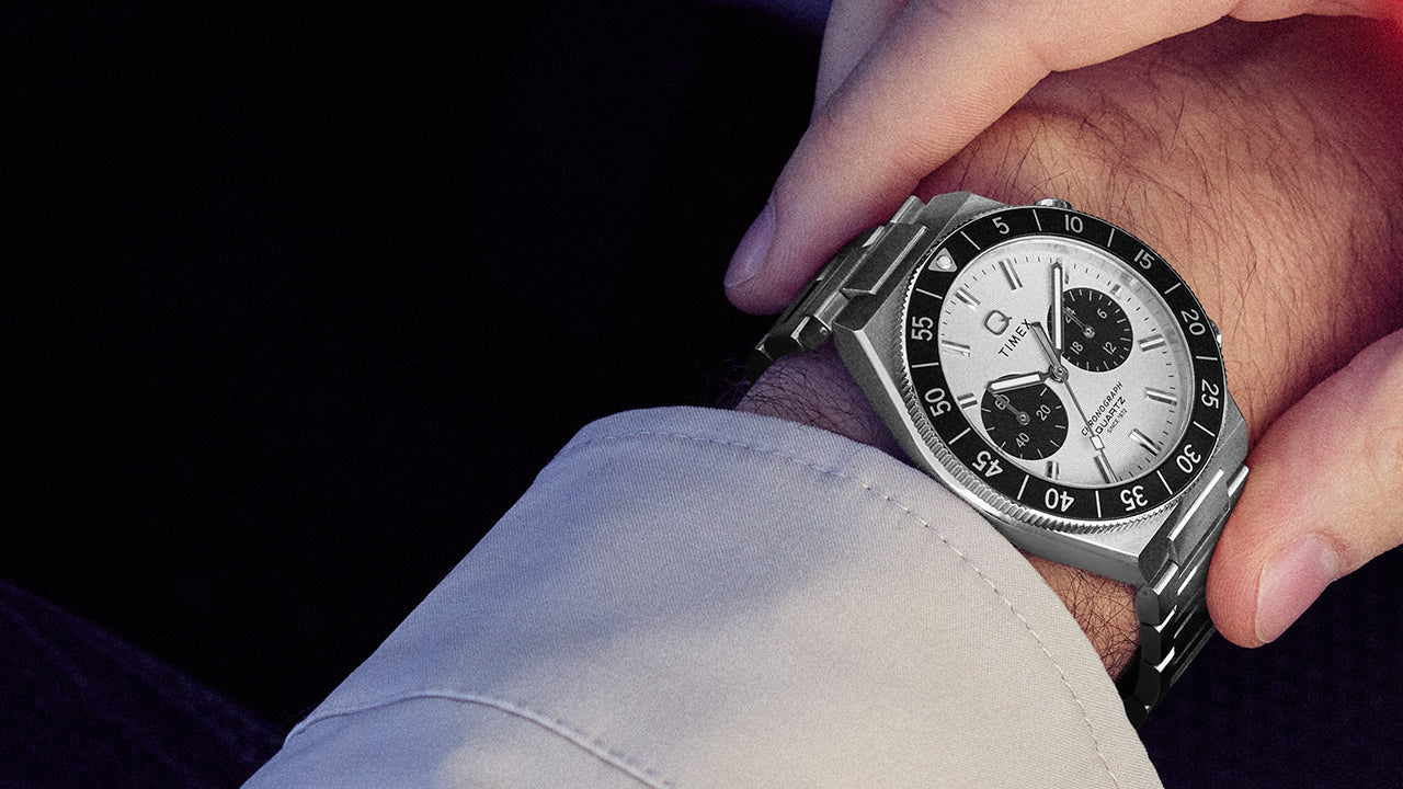 Close-up of the Q Timex Continental Chronograph on the wrist highlighting the stainless steel case, black bezel, and chronograph pushers.