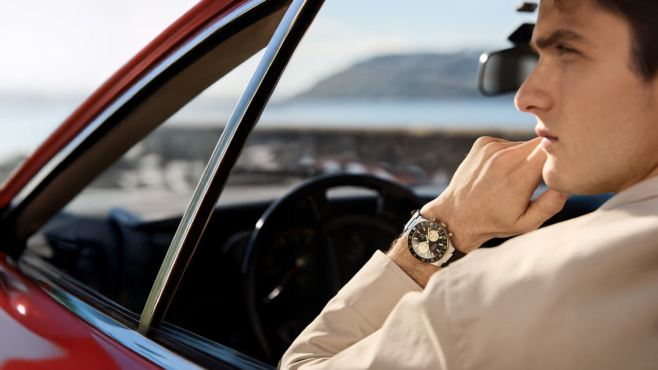 Q Timex® Continental Chronograph worn on wrist inside a vintage car, highlighting the black and champagne dial and leather strap.